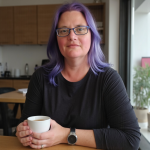 Woman with purple hair, glasses and a black top